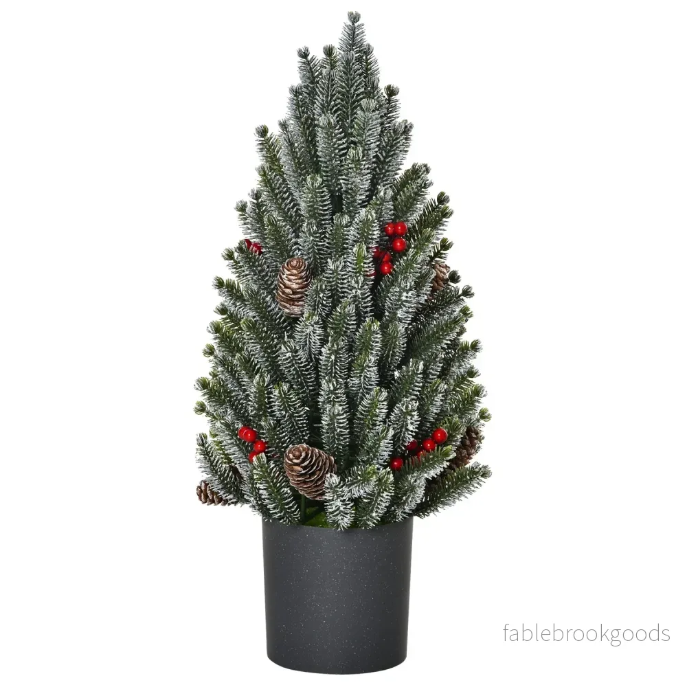 Snötäckt bordsjulgran med bär och tallkottar Snötäckt bordsjulgran med bär och tallkottar